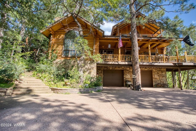 view of front of house featuring stairway, stone siding, driveway, and log exterior