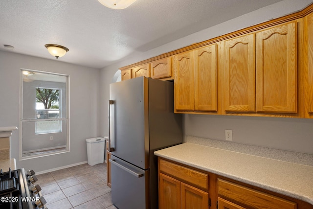 864 S 1st St E, Snowflake, AZ 85937 - kitchen featuring appliances with stainless steel finishes, light countertops, light tile patterned floors, a textured ceiling, and baseboards