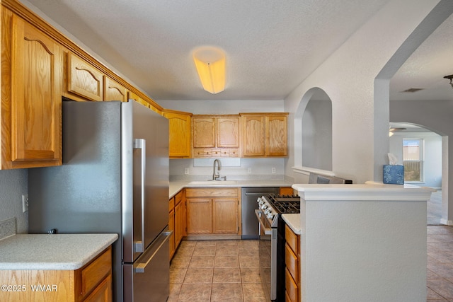 864 S 1st St E, Snowflake, AZ 85937 - kitchen featuring stainless steel appliances, light countertops, a sink, arched walkways, and light tile patterned flooring