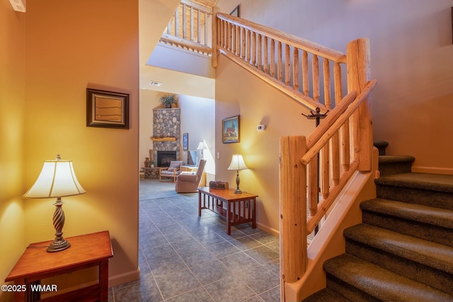 stairway featuring tile patterned flooring, baseboards, a fireplace, and a high ceiling