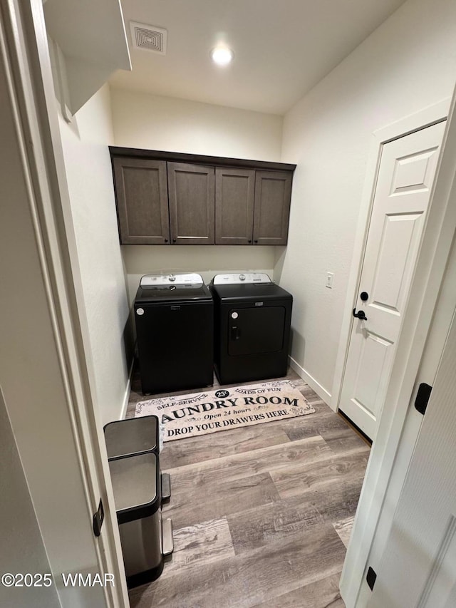 laundry area with visible vents, independent washer and dryer, wood finished floors, cabinet space, and baseboards