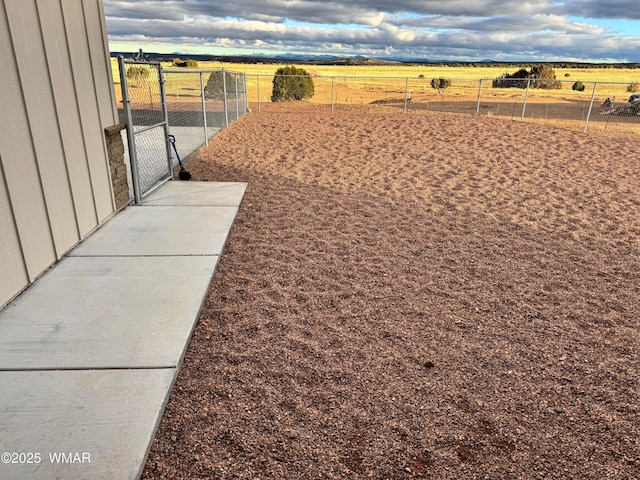 view of yard featuring a gate, a rural view, and fence