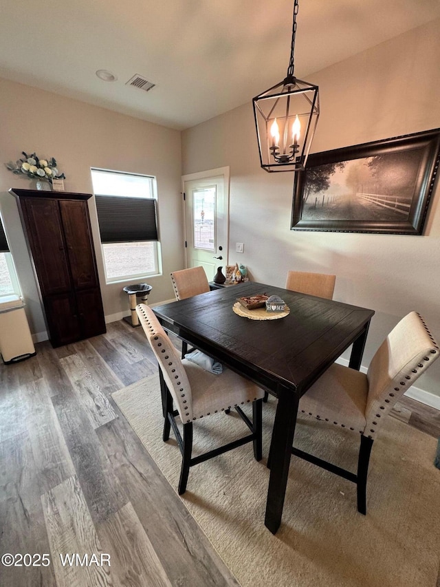 dining room with visible vents, wood finished floors, baseboards, and a chandelier