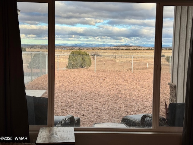 view of yard featuring a mountain view, a rural view, and fence