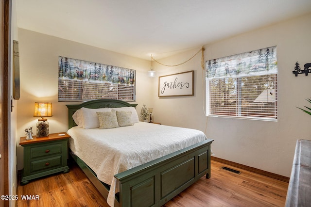 bedroom featuring light wood-type flooring, visible vents, and baseboards