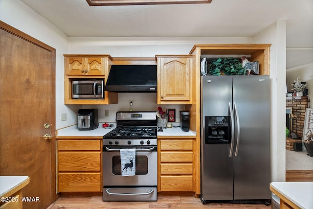 kitchen with under cabinet range hood, stainless steel appliances, light countertops, and light wood finished floors