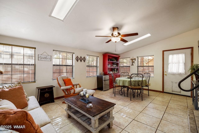 living area with light tile patterned floors, lofted ceiling with skylight, a wealth of natural light, and a ceiling fan