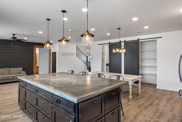 1738 W 7th St, Snowflake, AZ 85937 - kitchen featuring a barn door, a ceiling fan, a kitchen breakfast bar, light wood-style floors, and pendant lighting