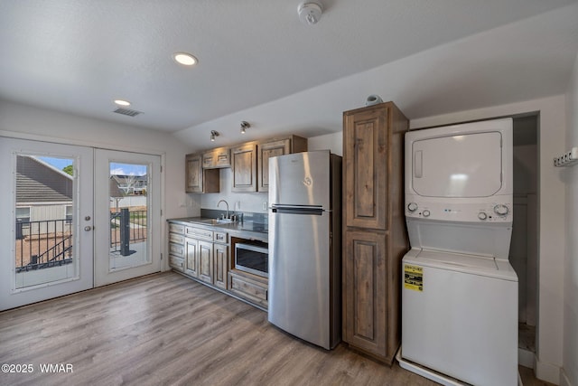 1738 W 7th St, Snowflake, AZ 85937 - kitchen with appliances with stainless steel finishes, stacked washer and clothes dryer, french doors, a sink, and light wood-style flooring
