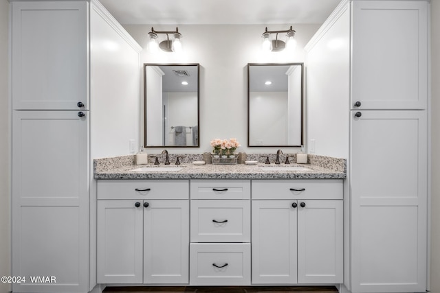 bathroom featuring visible vents, a sink, and double vanity