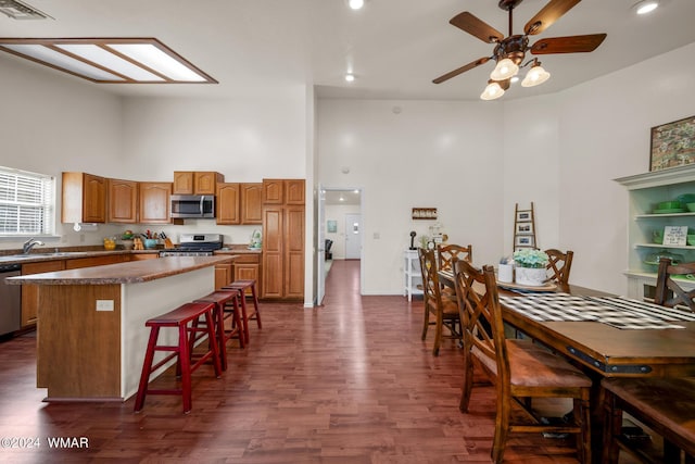 kitchen featuring brown cabinets, visible vents, appliances with stainless steel finishes, a kitchen island, and a kitchen bar