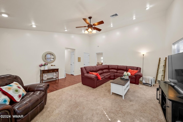 living room with recessed lighting, visible vents, light carpet, and a towering ceiling