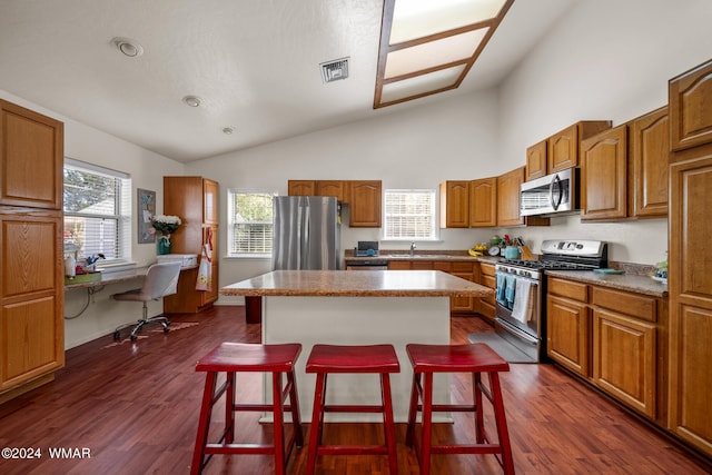 kitchen featuring visible vents, a kitchen island, appliances with stainless steel finishes, a breakfast bar, and light countertops