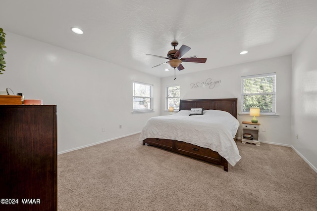 bedroom with baseboards, multiple windows, and light colored carpet