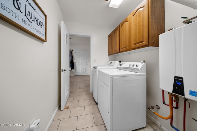 washroom with light tile patterned floors, tankless water heater, washing machine and clothes dryer, and cabinet space