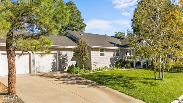 view of front of home with an attached garage, a shingled roof, a front lawn, and concrete driveway