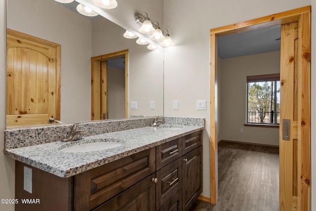 bathroom featuring double vanity, baseboards, a sink, and wood finished floors