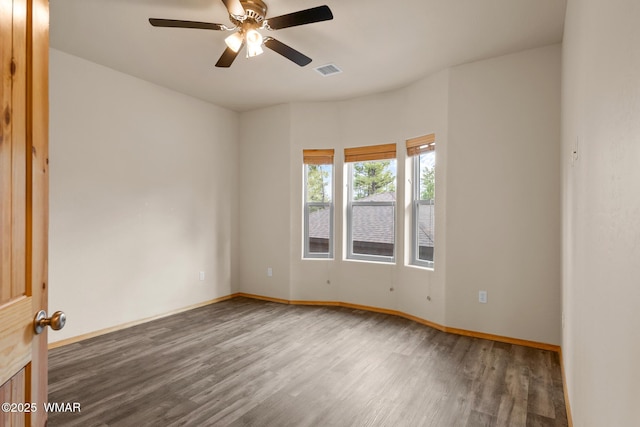 spare room with baseboards, visible vents, and wood finished floors