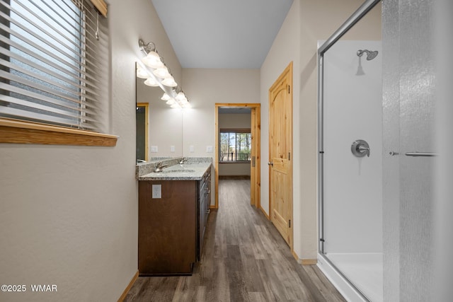 bathroom with a stall shower, wood finished floors, vanity, and baseboards