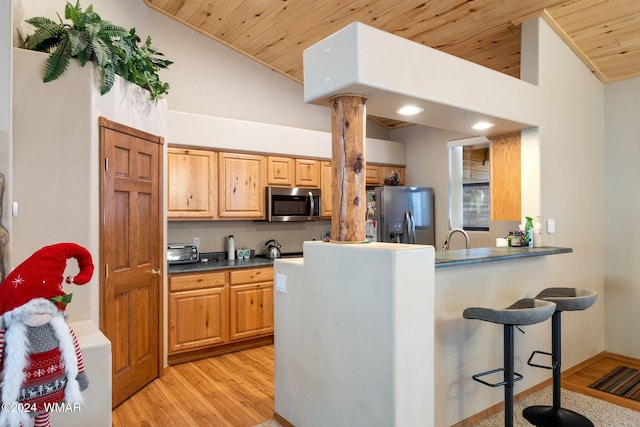 2740 W Maple Ln, Show Low, AZ 85901 - kitchen featuring dark countertops, light wood finished floors, a kitchen breakfast bar, stainless steel appliances, and wood ceiling