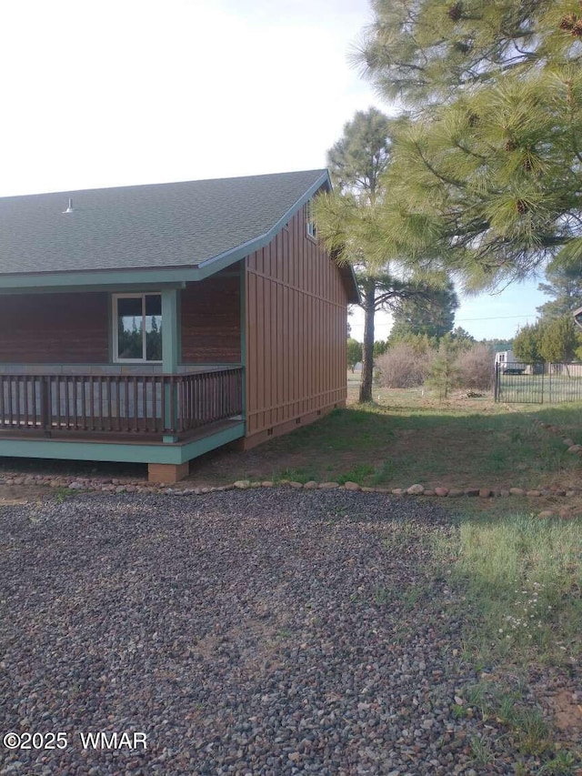 view of home's exterior featuring board and batten siding, roof with shingles, and fence