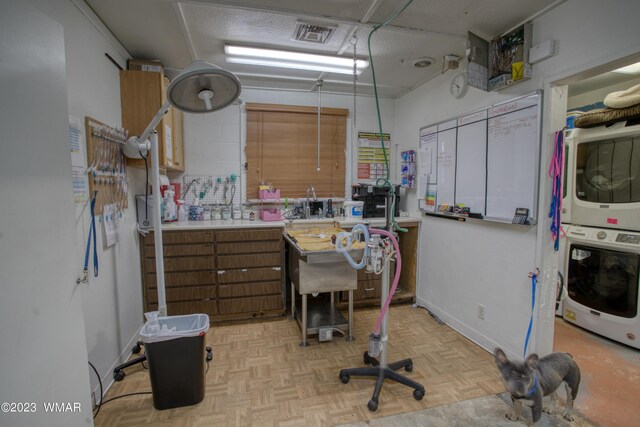 office area featuring baseboards, visible vents, and stacked washer / drying machine