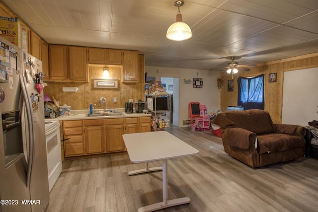 kitchen featuring light wood-style flooring, a sink, open floor plan, light countertops, and hanging light fixtures