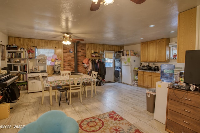 dining area featuring stacked washer / dryer, a wood stove, and ceiling fan