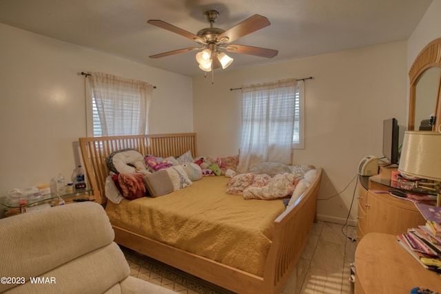 bedroom featuring a ceiling fan, multiple windows, and baseboards