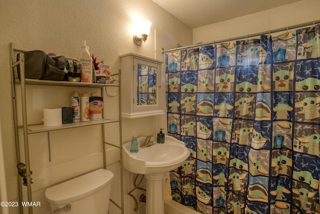 bathroom featuring curtained shower, a textured wall, and toilet