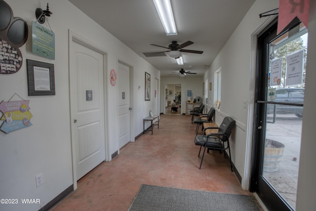 hall featuring finished concrete flooring and baseboards