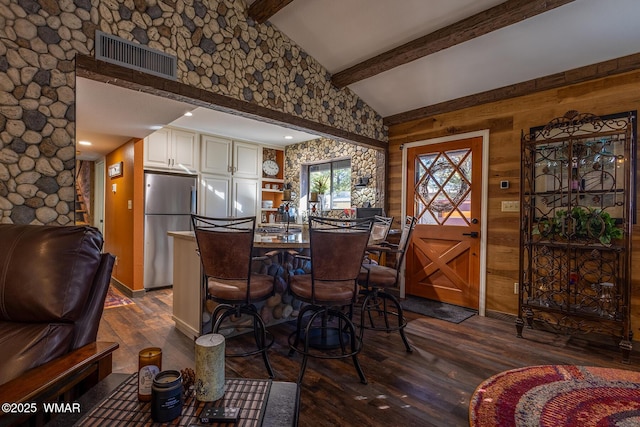 dining room featuring vaulted ceiling with beams, dark wood-style floors, and visible vents