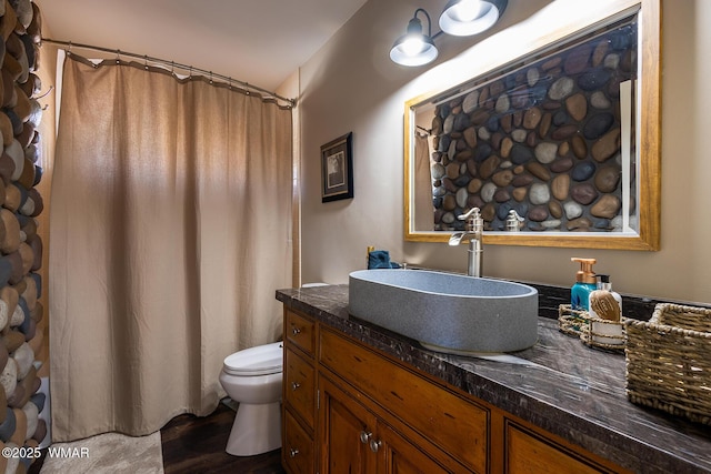 bathroom featuring toilet, wood finished floors, and vanity