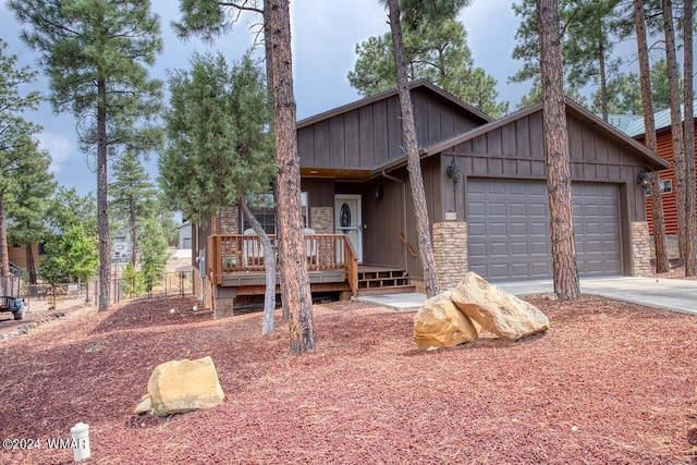 view of front of house featuring stone siding, fence, an attached garage, and concrete driveway