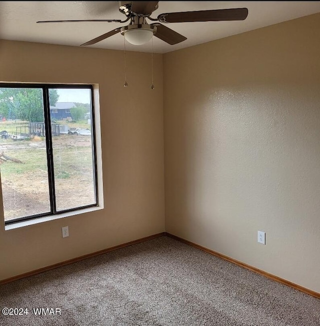 carpeted empty room with ceiling fan and baseboards