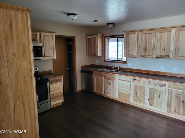 kitchen with dark countertops, light brown cabinets, appliances with stainless steel finishes, and a sink