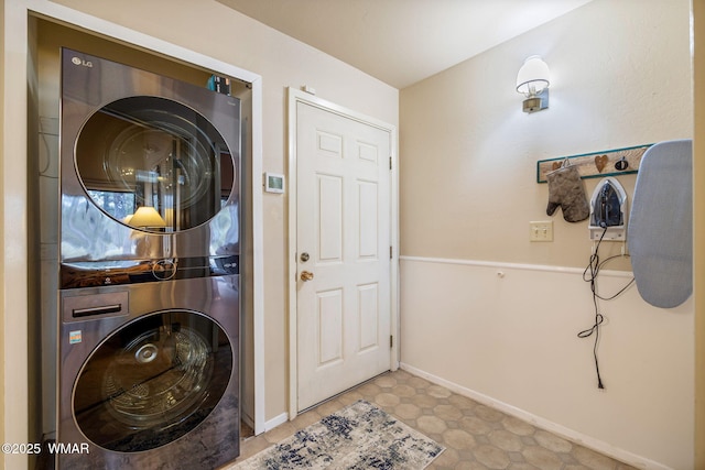 laundry area with laundry area, stacked washer and clothes dryer, and baseboards