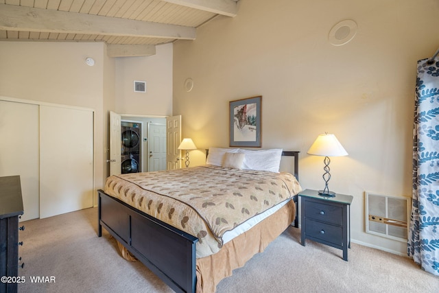 bedroom with a closet, carpet flooring, visible vents, and stacked washer / drying machine