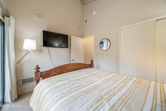 bedroom featuring a towering ceiling, a closet, carpet flooring, and visible vents