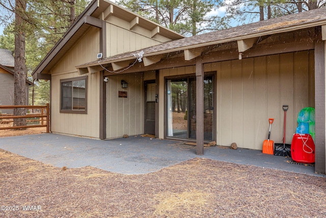 doorway to property featuring a patio area and a shingled roof