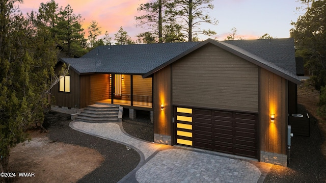 view of front of home featuring decorative driveway, an attached garage, roof with shingles, and crawl space