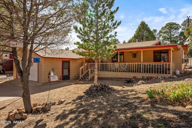 view of front of property featuring concrete driveway, a shingled roof, and covered porch