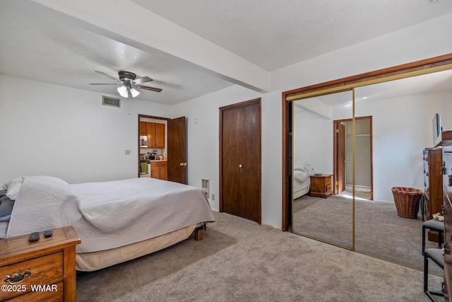 bedroom featuring a textured ceiling, ceiling fan, visible vents, and carpet floors