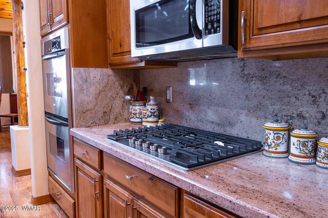 6757 Cheney Ranch Loop, Show Low, AZ 85901 - kitchen with appliances with stainless steel finishes, brown cabinetry, light stone countertops, and backsplash