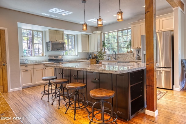 2020 S Pleasantview Dr, Show Low, AZ 85901 - kitchen featuring stainless steel appliances, light wood-style flooring, a kitchen island, light stone counters, and a breakfast bar