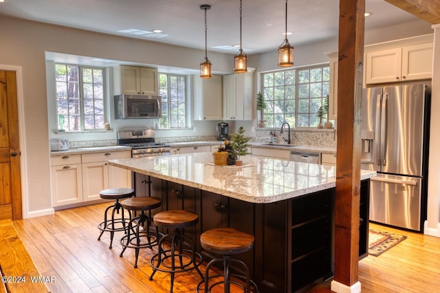 2020 S Pleasantview Dr, Show Low, AZ 85901 - kitchen featuring stainless steel appliances, a sink, light wood-style floors, a kitchen island, and a kitchen bar