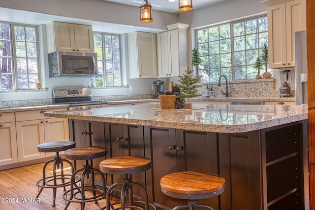 2020 S Pleasantview Dr, Show Low, AZ 85901 - kitchen featuring stainless steel appliances, a breakfast bar area, light stone counters, light wood-type flooring, and a center island