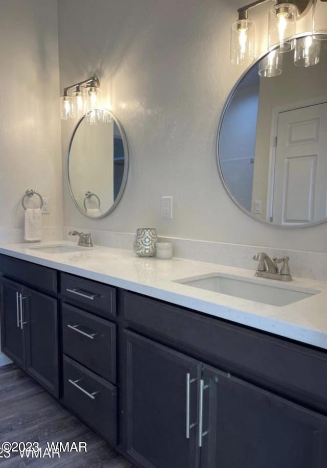 bathroom featuring double vanity, a sink, and wood finished floors