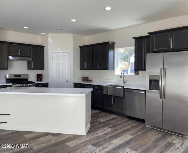 kitchen with stainless steel appliances, dark cabinetry, light countertops, and under cabinet range hood