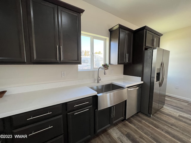 kitchen with dark wood finished floors, light countertops, appliances with stainless steel finishes, a sink, and dark cabinets